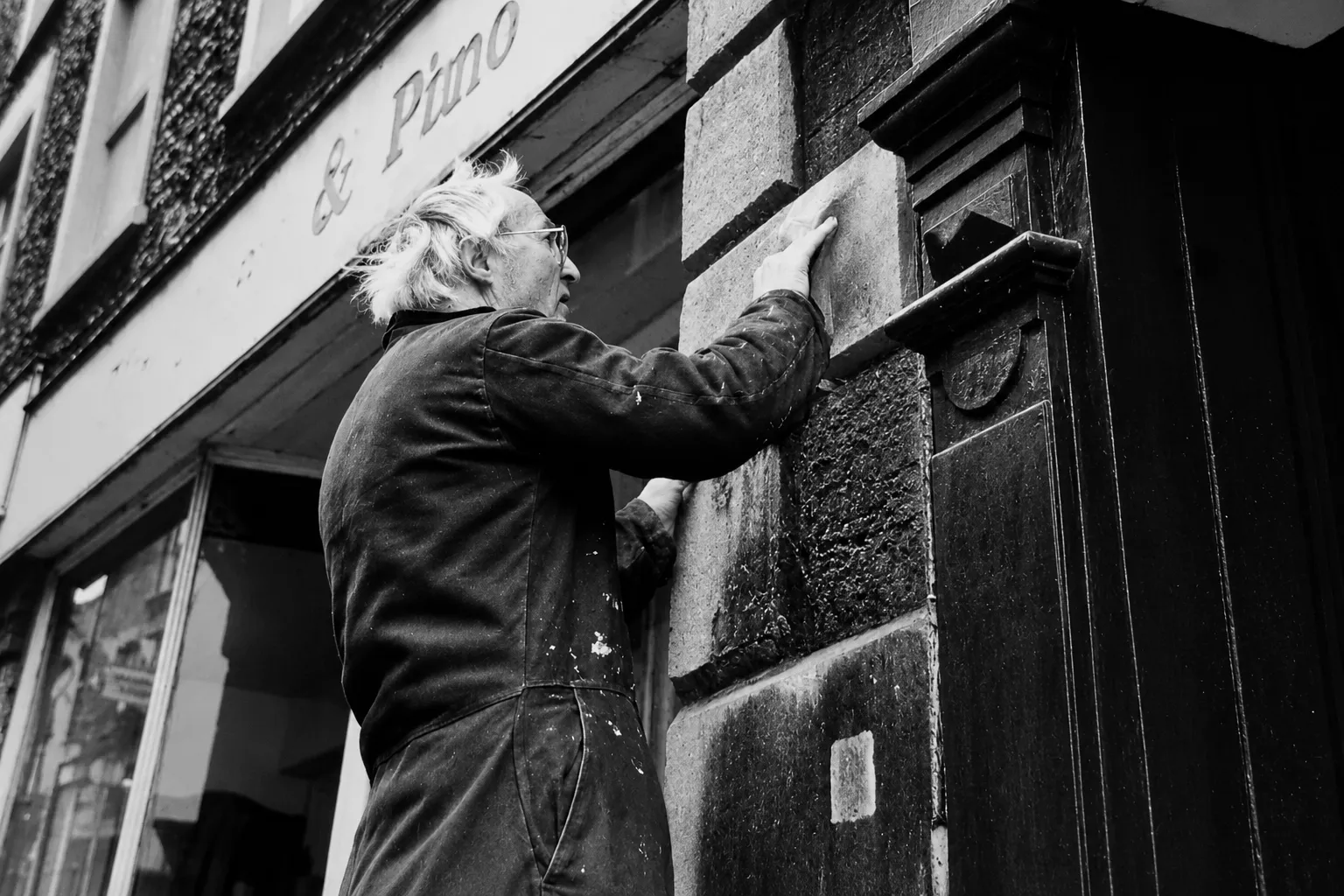 Reg Ling fixing a wall plaque that marks the original site of the Cockey lamp on Catherine Hill.